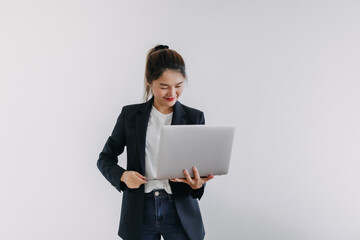 Happy asian Thai business woman wear blazer holding laptop, smiling and looking at notebook, typing keyboard isolated over white background wall.