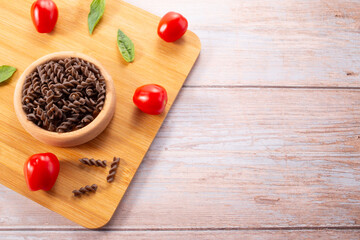 Organic Buckwheat Fusilli pasta,tomatoes cherry,basil leaf,on wooden background.Gluten free noodles.Healthy food concept