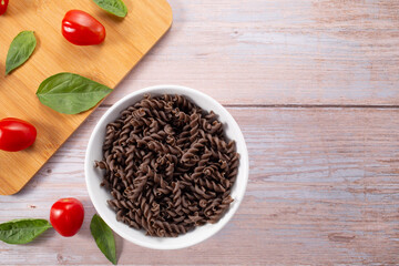 Organic Buckwheat Fusilli pasta,tomatoes cherry,basil leaf,on wooden background.Gluten free noodles.Healthy food concept