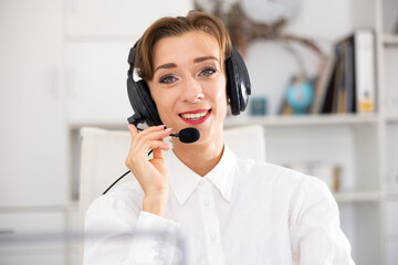 Naklejka premium Office worker woman is working at a computer and talking by headset with client in the office