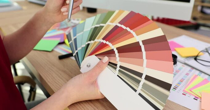 Hands of female designer touch multicolored palette samples
