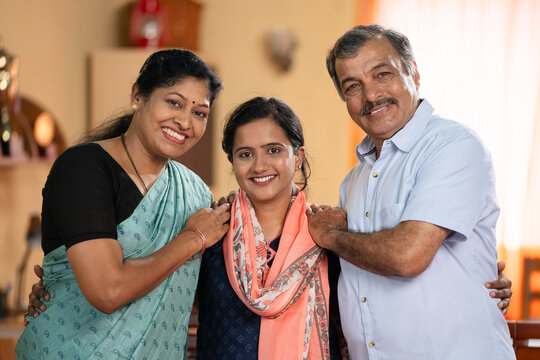 Happy smiling Middle class parents with daughter looking camera at home - concept of family bonding, relationship and generations