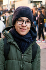 Smiling young boy wearing glasses and winter clothes at the school entrance, ready for a new day.