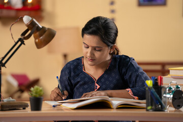 Indian young teenager girl using mobile phone for studying at home - concept of exam preparation,...
