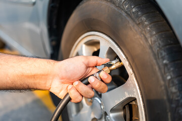 Man driver hand inflating tires. Fill Air station service for vehicle tires. Checking air pressure car wheels maintenance and safety