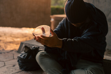 Homeless man on the street waiting for help food and money from people volunteer foundation donate. Poor tired stressed depressed hungry homeless man