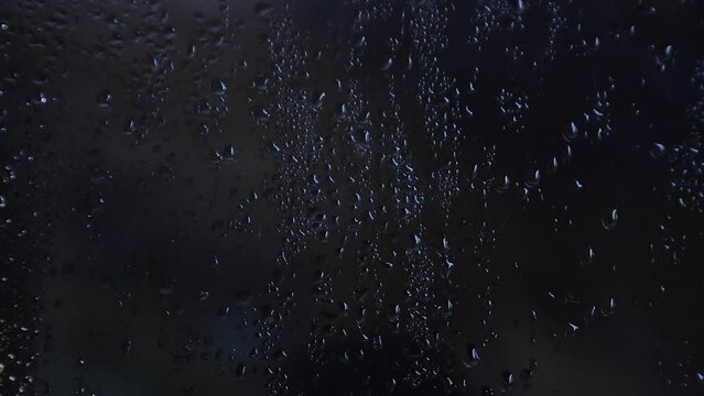 Foggy glass with water vapor, fog, flowing. Window with water drops Raindrops on a dark background