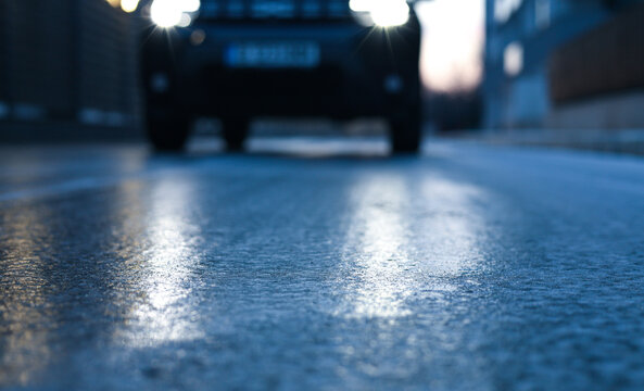 Glazed frost on the asphalt. icy road danger for driving. Close up photo of a road covered with ice after a snowfall and freezing rain.