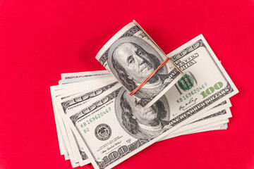 Roll of american dollars on a red background. Financial concept.