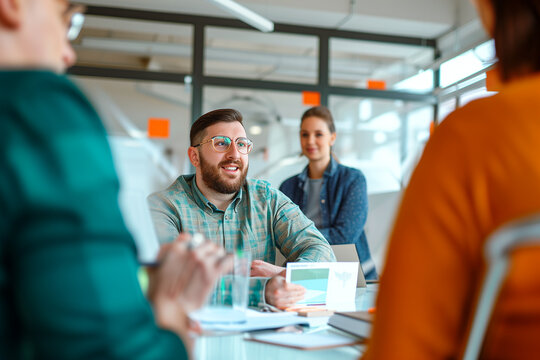 An adult man with Down syndrome presenting a project surrounded by colleagues in a bright and modern office. A person with a disability at work.