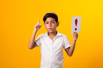 Kid boy holding exclamation point card. Education and curiosity concept