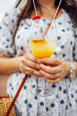 Close up of female hands holding glasses of acohol cocktail with fresh fruts and berries