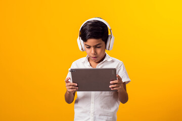 Kid boy with headphone and tablet playing video game. Leisure and gadget addiction concept