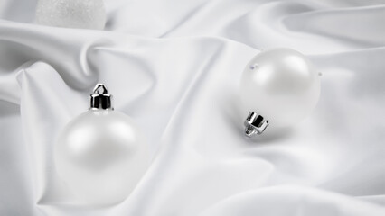 Obraz na płótnie Canvas White Christmas baubles decoration on white silk background. Holiday concept.
