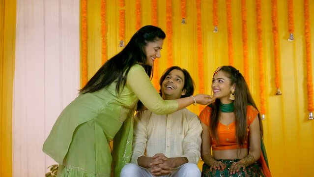Lovely Indian aunt feeding Barfi to a young couple - traditional sweet  Hindu marriage rituals  wishing good luck. Engaged pair receiving blessings from a close relative - Indian wedding ceremony  ...