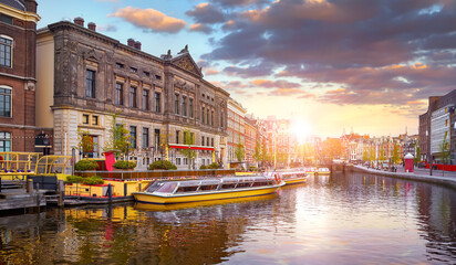 Amsterdam, Holland, Netherlands. Amstel river, canals and boats against evening dusk sunset sky cityscape. Pleasure of amsterdam for touristic tours entertainment travel - obrazy, fototapety, plakaty