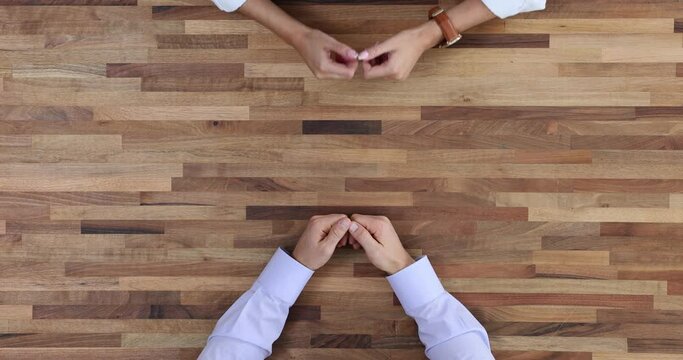 Two Negotiators With Folded Hand Man And Woman, Are Negotiating At Table Top View