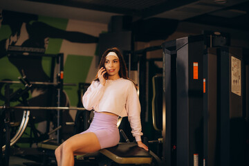 Sporty girl talking by the mobile phone in gym.