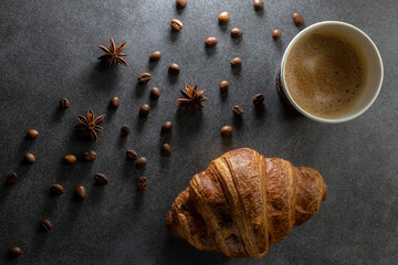 Croissant and cup of coffee on dark background.Top view food
