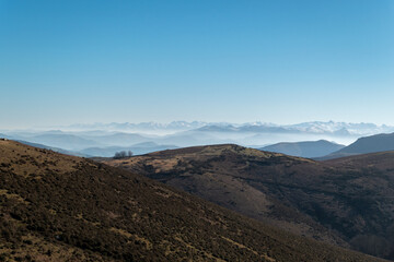 Montanhas em Artzamendi em Itxassou no País Basco com algumas trilhas de terra batida sobre a mesma e neve ao fundo nos picos das montanhas