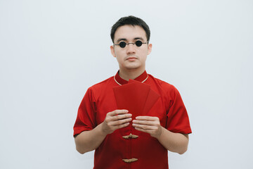 Asian man wearing traditional costume holding angpao or red monetary gift and looking at the camera...