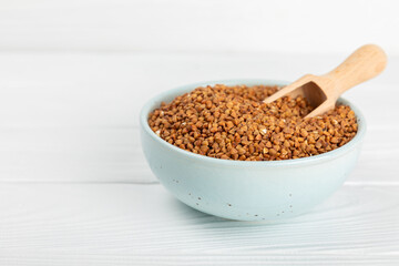 Raw buckwheat in a bowl on a textured wooden background. Wheat grains, porridge, cereals, raw buckwheat in a plate. Healthy food. Porridge. Diet. Organic cerea. Space for text.Copy space.