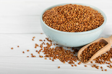 Raw buckwheat in a bowl on a textured wooden background. Wheat grains, porridge, cereals, raw buckwheat in a plate. Healthy food. Porridge. Diet. Organic cerea. Space for text.Copy space.