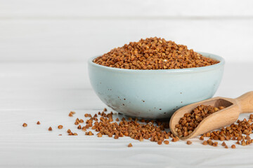 Raw buckwheat in a bowl on a textured wooden background. Wheat grains, porridge, cereals, raw buckwheat in a plate. Healthy food. Porridge. Diet. Organic cerea. Space for text.Copy space.