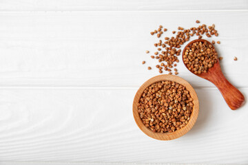 Raw buckwheat in a bowl on a textured wooden background. Wheat grains, porridge, cereals, raw buckwheat in a plate. Healthy food. Porridge. Diet. Organic cerea. Space for text.Copy space.