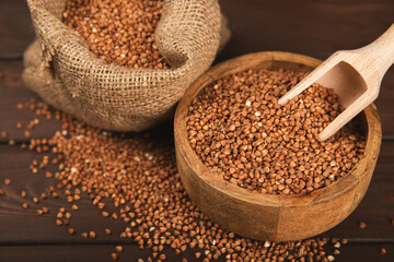 Raw buckwheat in a bowl on a textured wooden background. Wheat grains, porridge, cereals, raw buckwheat in a plate. Healthy food. Porridge. Diet. Organic cerea. Space for text.Copy space.