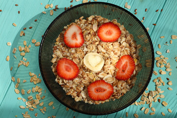 Oatmeal with slices of strawberry on a turquoise wooden background.Vegan breakfast