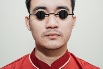 Portrait of Asian man wearing Cheongsam and black rounded vintage sunglasses