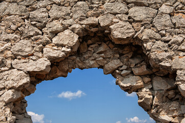 Ancient brick old stones wall arch with the sky as the background