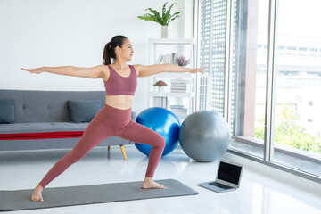 Beautiful smiling Female wearing sportswear exercise training yoga in living room. Attractive asian...