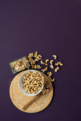 Cashew nuts on the violet background.Vertical format.Copy space