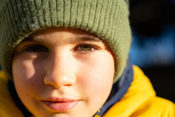 Portrait of boy in winter with green eyes yellow coat and green hat