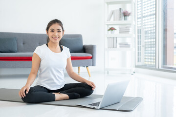 Fototapeta na wymiar Beautiful smiling Female wearing sportswear exercise training yoga in living room. Attractive asian young fitness woman stretching warming up before workout at home.