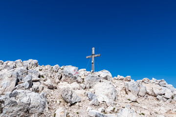 Summit cross of majestic mountain peak Mangart (Mangrt) in Julian Alps, Friuli Venezia Giulia, border Slovenia Italy. Climb rugged extreme alpine terrain in Triglav National Park. Wanderlust in Alps - obrazy, fototapety, plakaty
