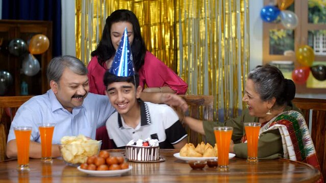 An Indian grandfather feeding a cake to his lovely grandson - celebration time  happy family  small family . A happy joint Indian family enjoying a birthday party - leisure time  togetherness and b...