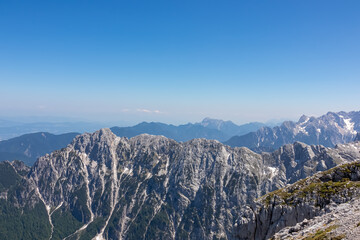 Panorama on top of untamed mountain peak mount Mangart (Mangrt), border Italy Slovenia. Scenic view of majestic mountain peaks of Julian Alps and Karawanks Pohorje. Climb rugged extreme alpine terrain - obrazy, fototapety, plakaty