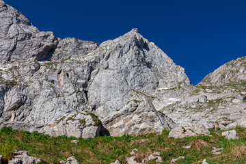 Scenic hiking trail from Fusine Lake to Mangart saddle in Tarvisio, Julian Alps, Friuli Venezia Giulia, Italy, Europe. Rugged mountain rock formations on extreme alpine terrain in summer. Wanderlust - obrazy, fototapety, plakaty
