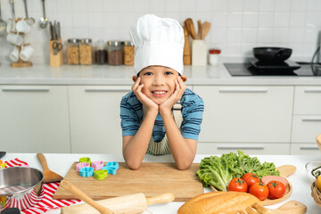 Asian Little chef boy cooking breakfast in the kitchen. Funny kids are preparing food with...