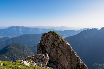 Fototapeta na wymiar Massive rock formation with aerial view of Gailtal Alps and Karwanks mountains in Carinthia Austria. Seen from hiking trail to Mangart saddle in Julian Alps in Tarvisio, Friuli-Venezia Giulia, Italy