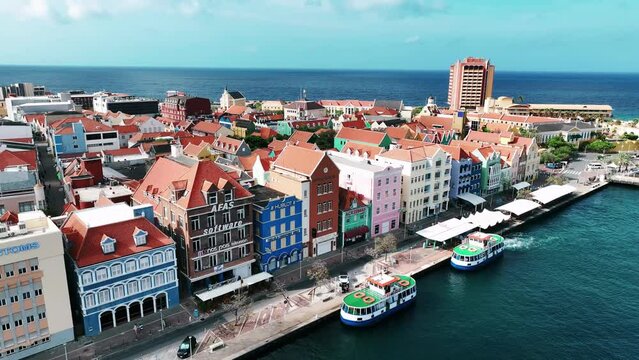The drone is flying away from the old colorfull houses on the trade quay (handelskade) in Willemstad Curacao Aerial Footage 4K