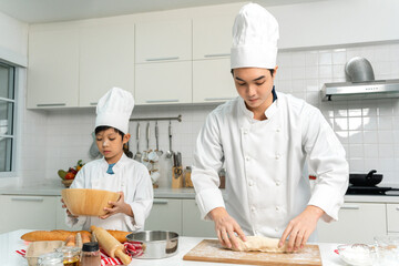 Young handsome asian man chef cooking breakfast in the kitchen. Happy asian man preparing food with ingredient. Chef in uniform in the kitchen.