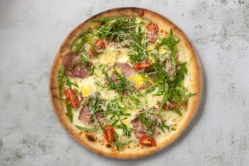 Isolated italian pizza with arugula,cherry tomatoes,egg,bacon.Top view