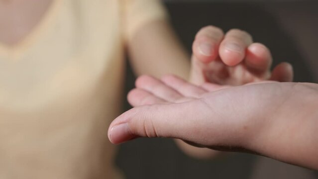 Give a help hands for mum. A view of woman hand in girl's hand indoor. A concept of family love and support.