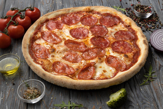 Delicious pepperoni pizza on a wooden background with ingredients.Italian food