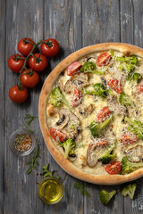 Pizza with broccoli,cherry tomatoes,chicken breast and mushroom.Top view.Vertical format