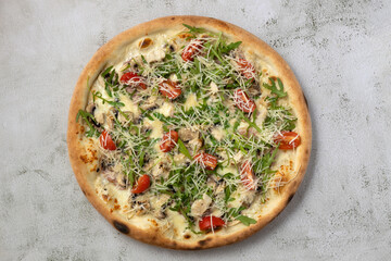 Isolated italian pizza with cherry tomatoes, arugula and chicken breast.Top view